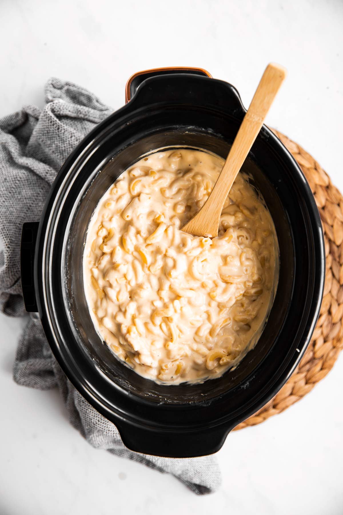 overhead view on crockpot with Mac and cheese and wooden spoon on placemat