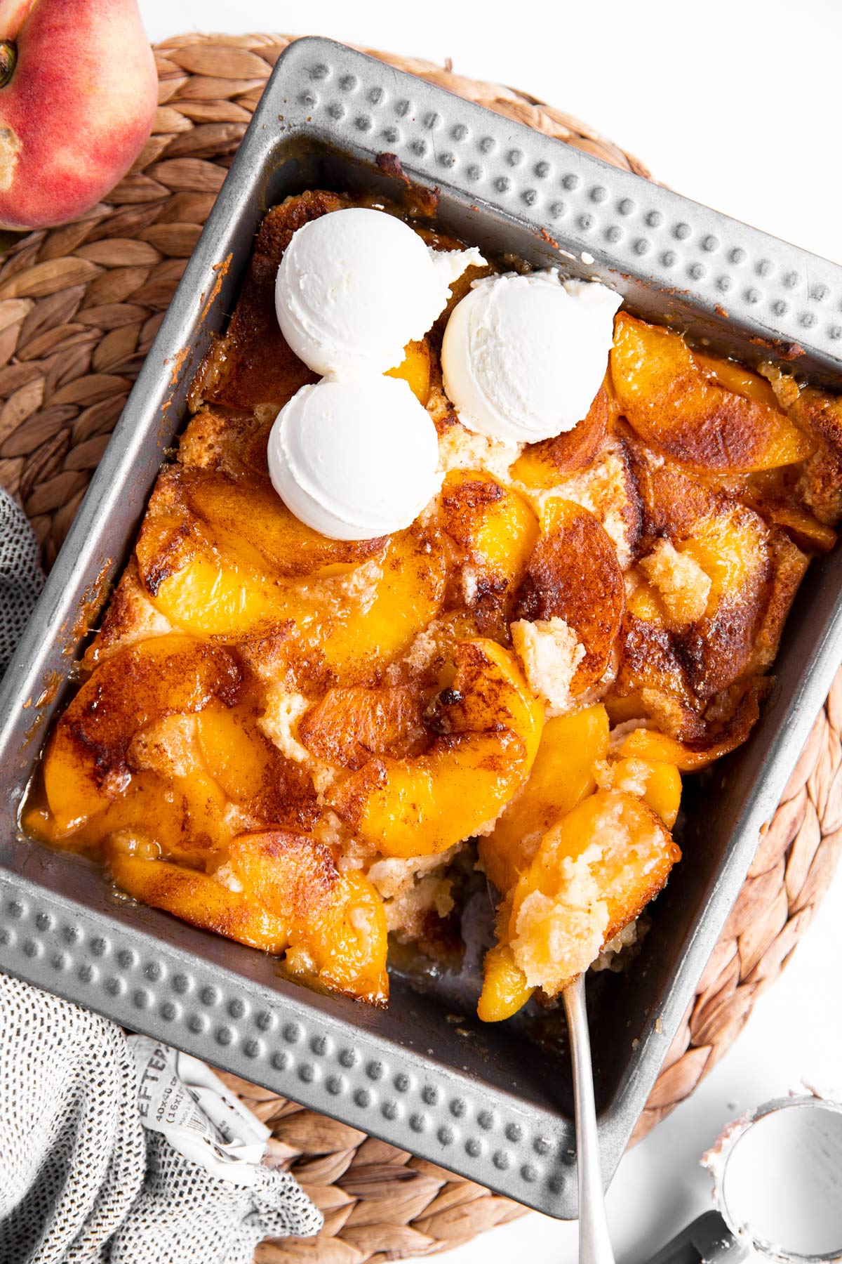 overhead view of peach cobbler in pan with ice cream