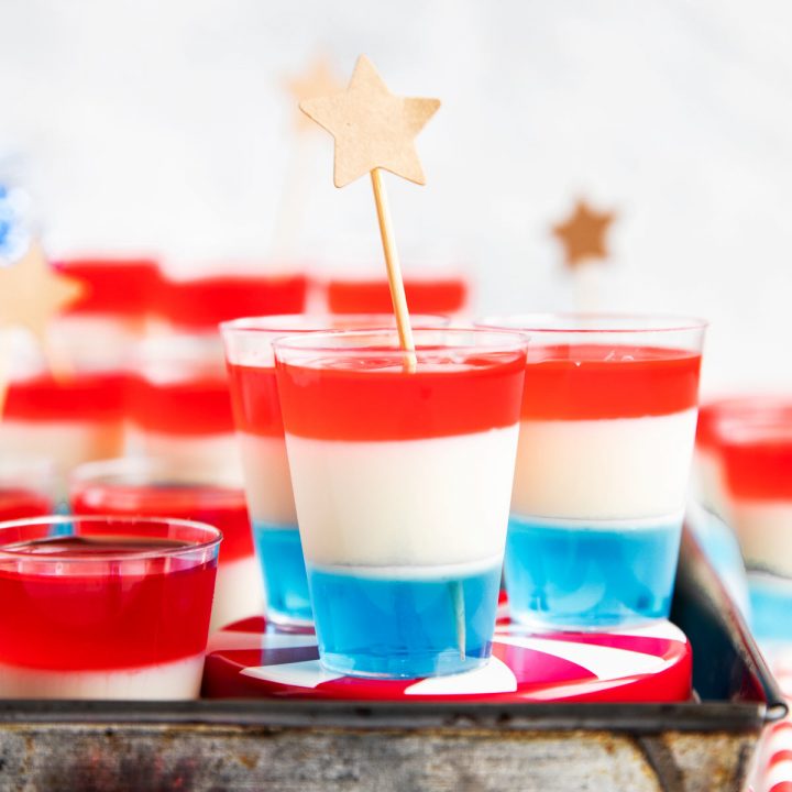 several plastic shot glasses with layered jello and star decor