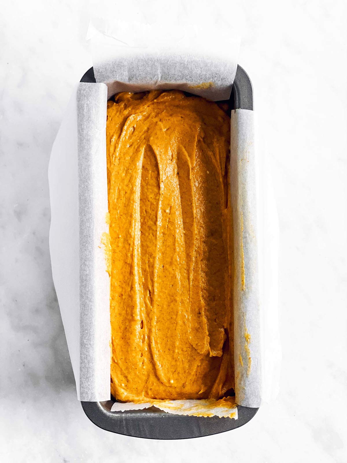 loaf pan with batter for pumpkin bread