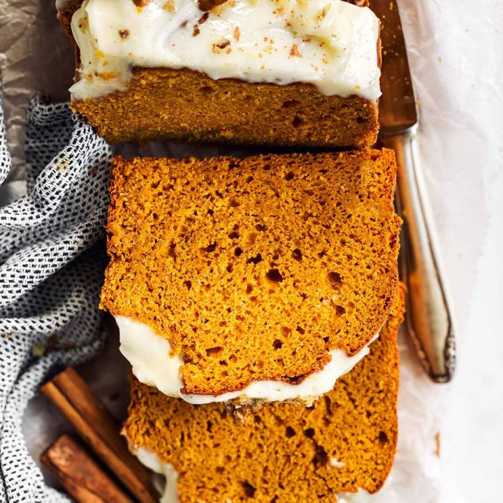 sliced pumpkin bread on chopping board with frosting