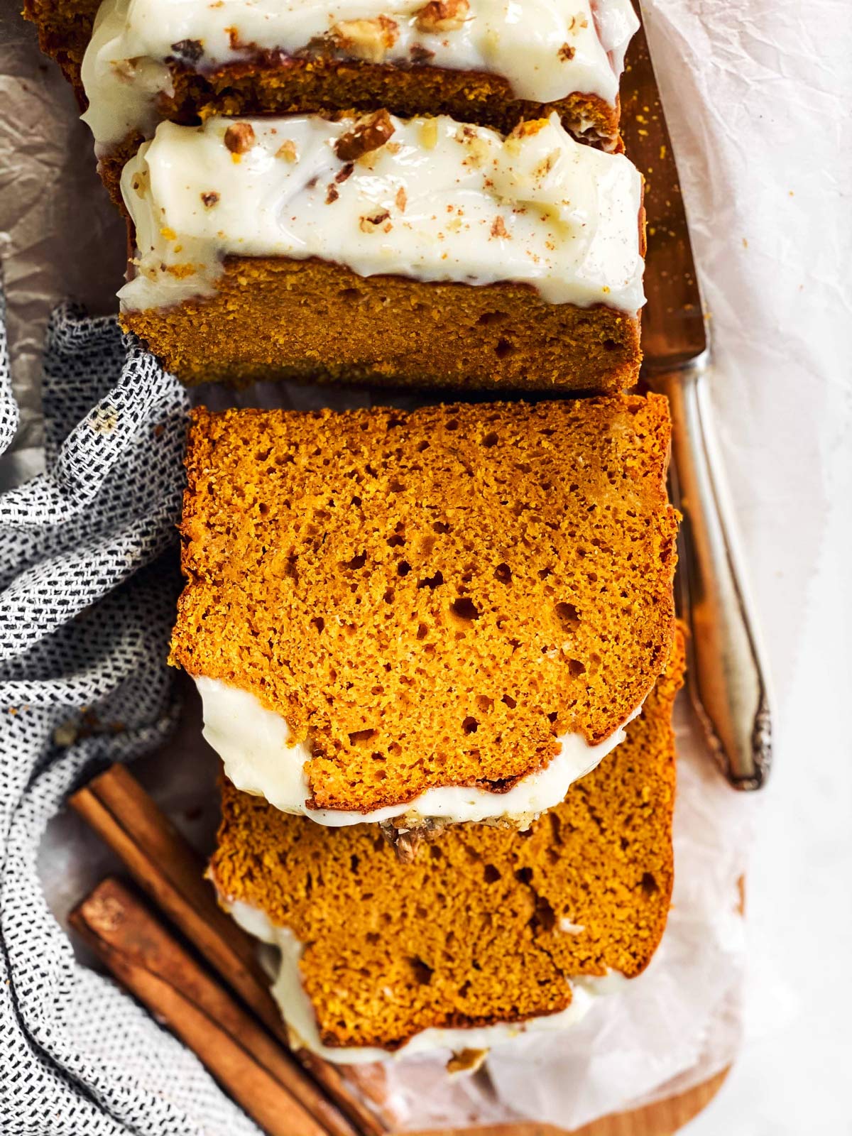 sliced pumpkin bread on chopping board with frosting