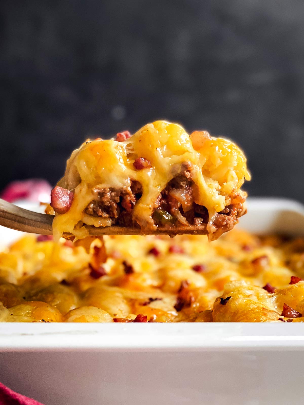 scoop of bacon cheeseburger tater tot c casserole on wooden spatula