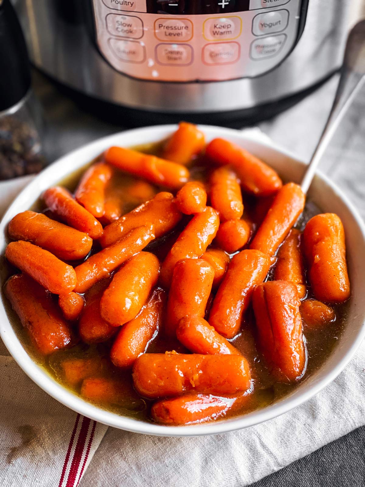 bowl with glazed carrots in front of instant pot