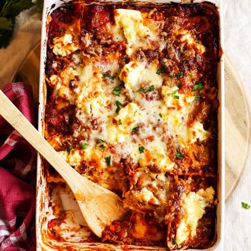 white casserole dish with ravioli lasagna on tablecloth