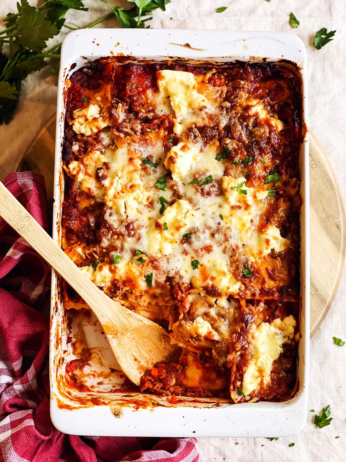 white casserole dish with ravioli lasagna on tablecloth