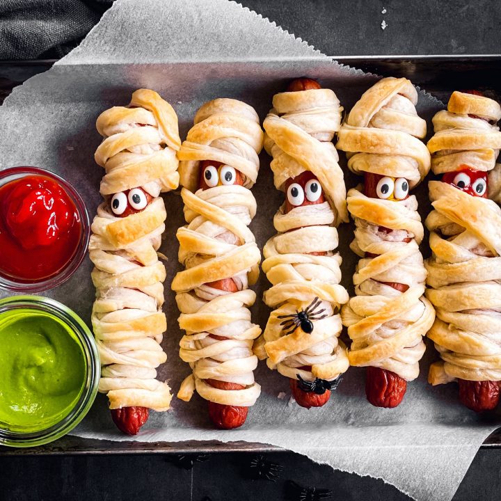 overhead view of small metal pan with mummy hot dogs on dark background