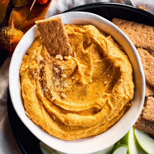 overhead view of white bowl with garnished pumpkin dip