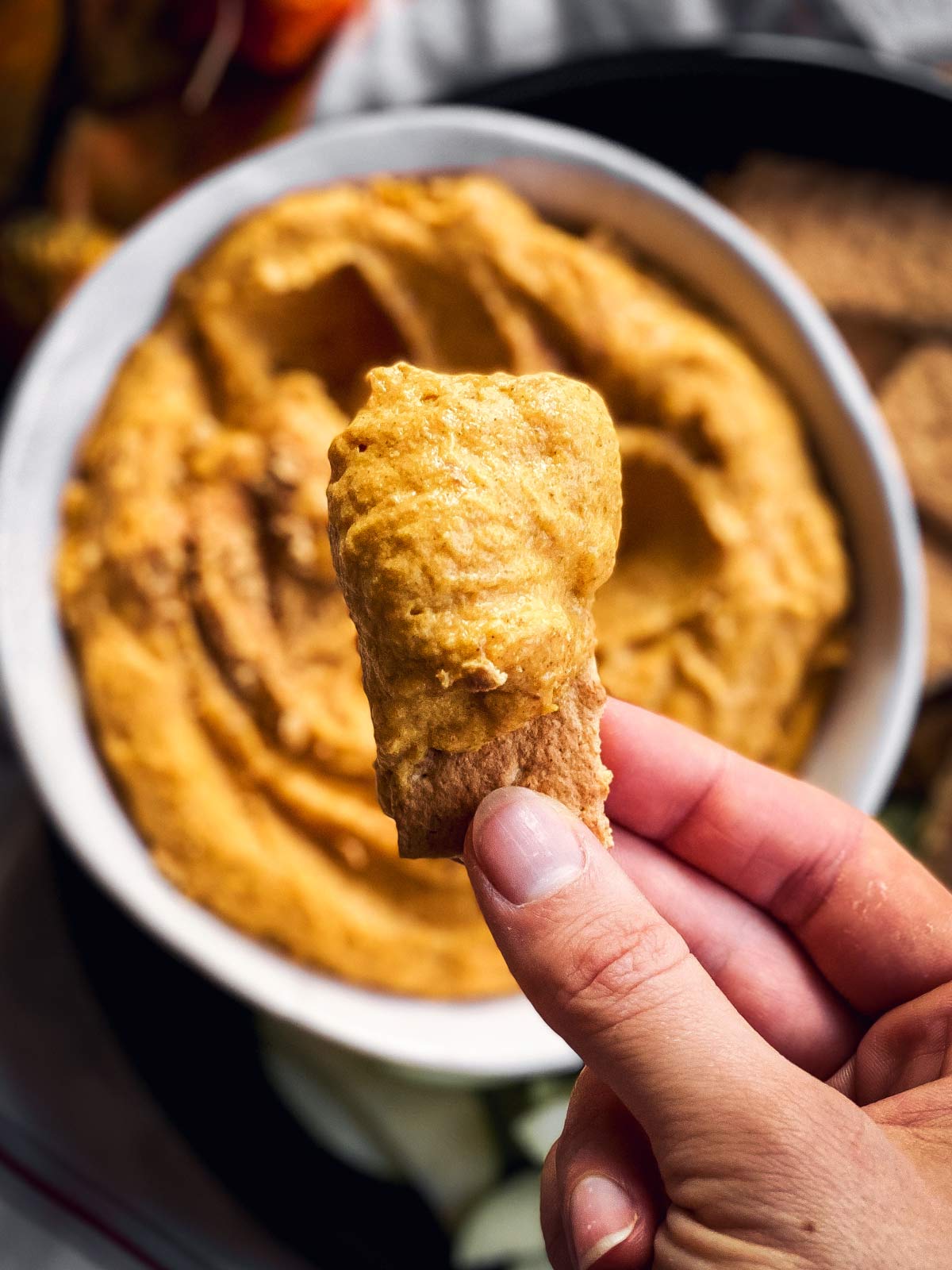 female hand holding graham cracker loaded with pumpkin fluff dip