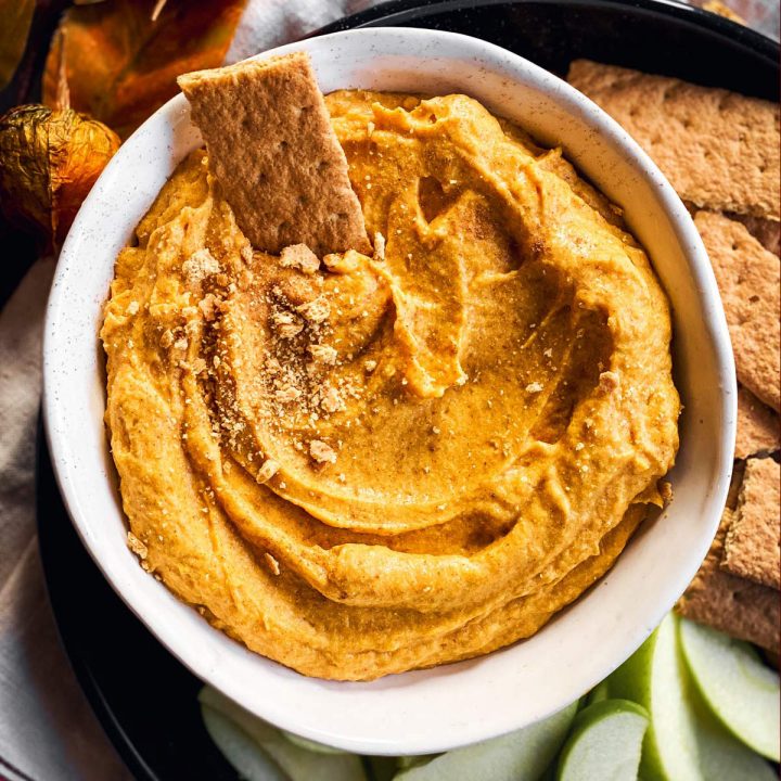 overhead view of white bowl with garnished pumpkin dip