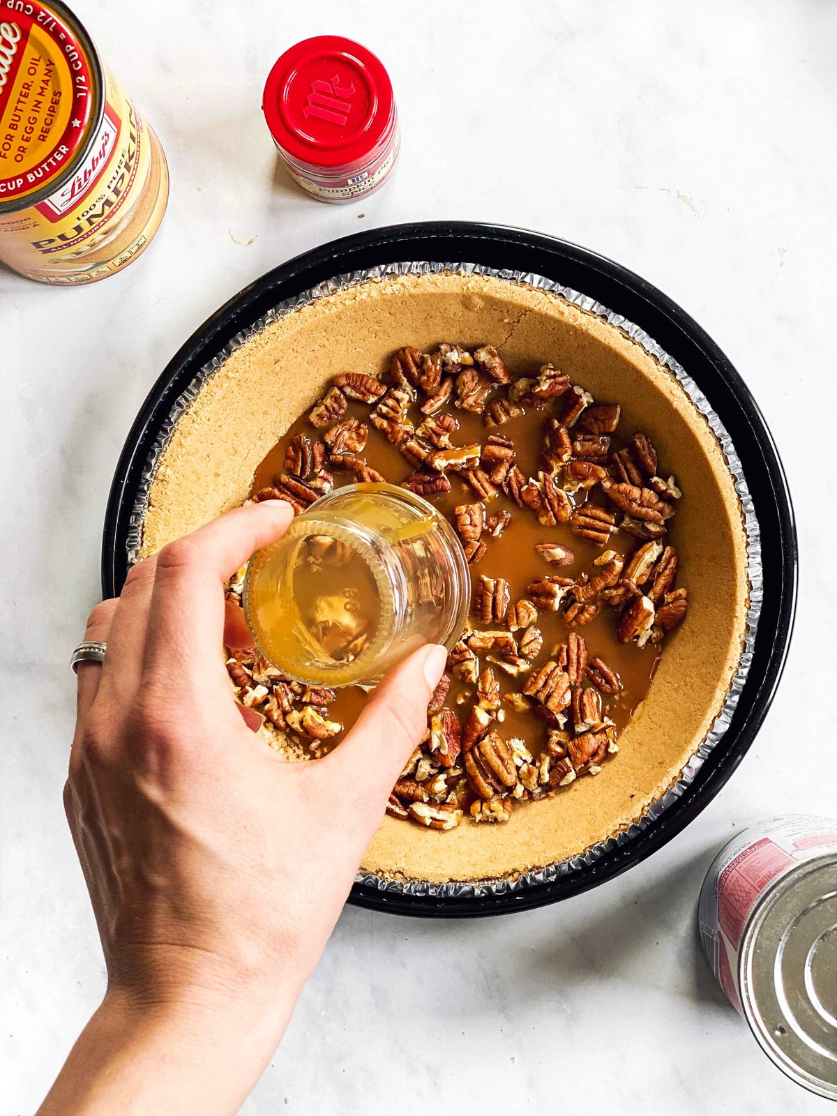 female hand adding caramel to graham cracker crust