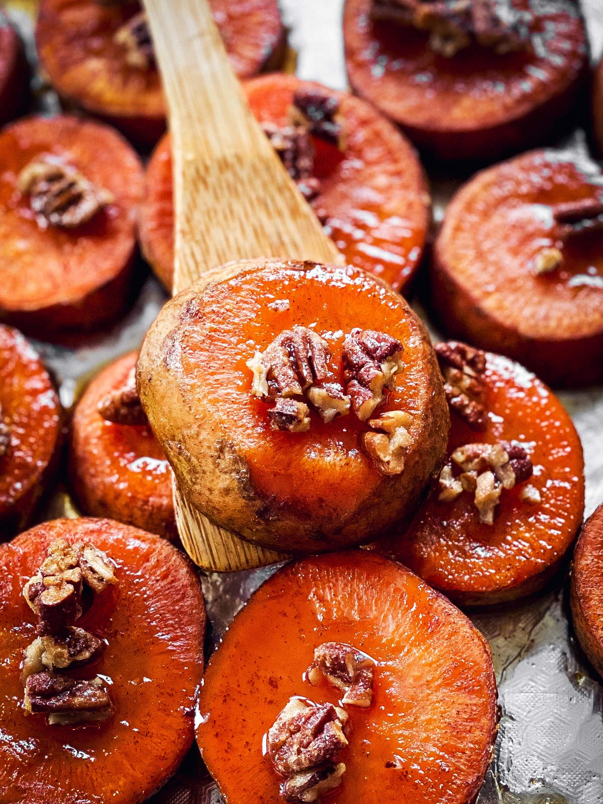 close up of wooden spatula with baked sweet potato slice on top