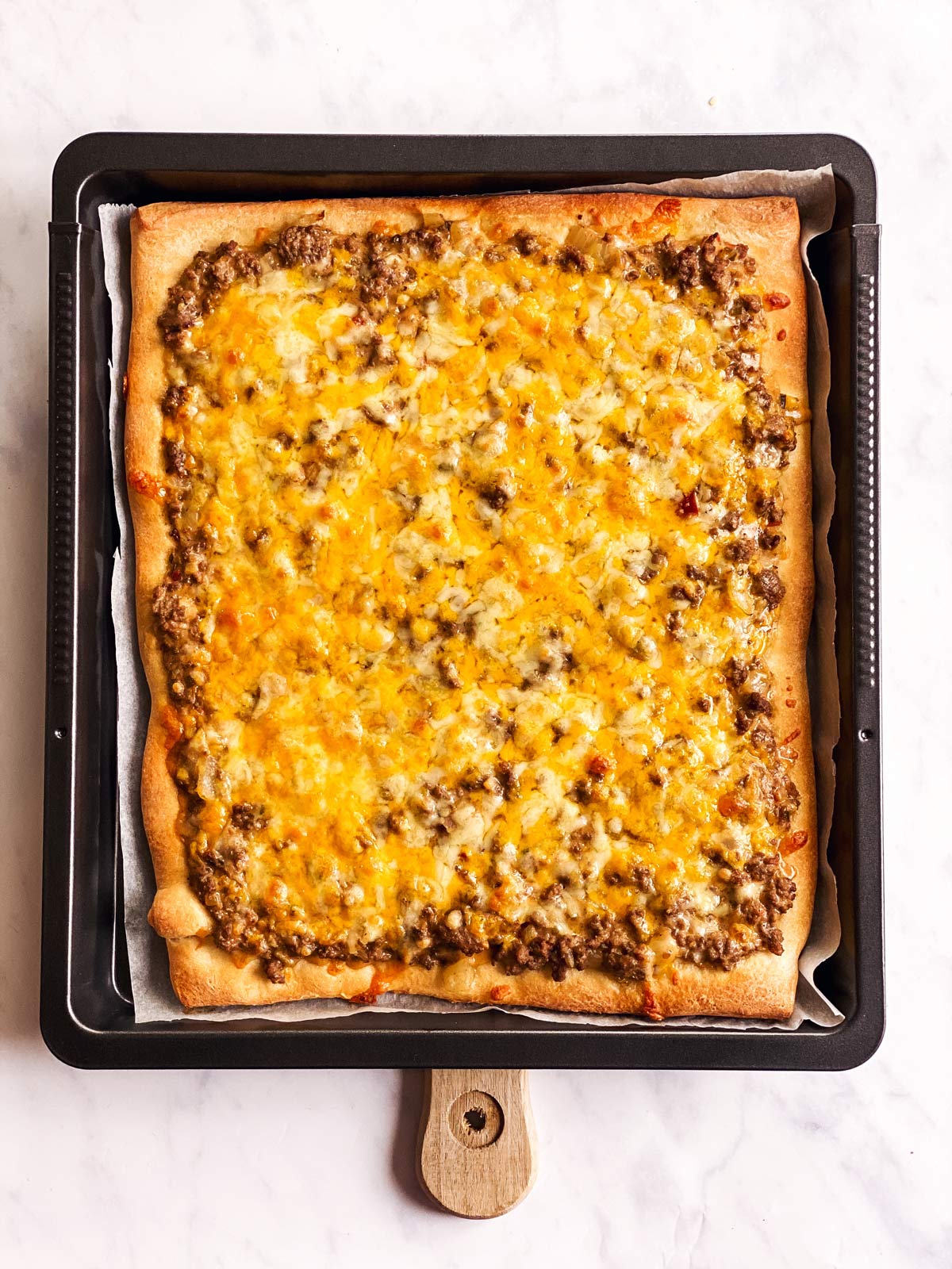 baked Big Mac pizza on dark baking pan