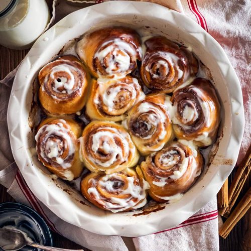 round pan with baked cinnamon rolls on wooden surface