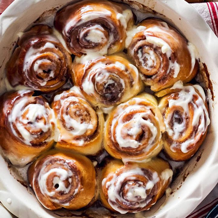 round pan with baked cinnamon rolls on wooden surface
