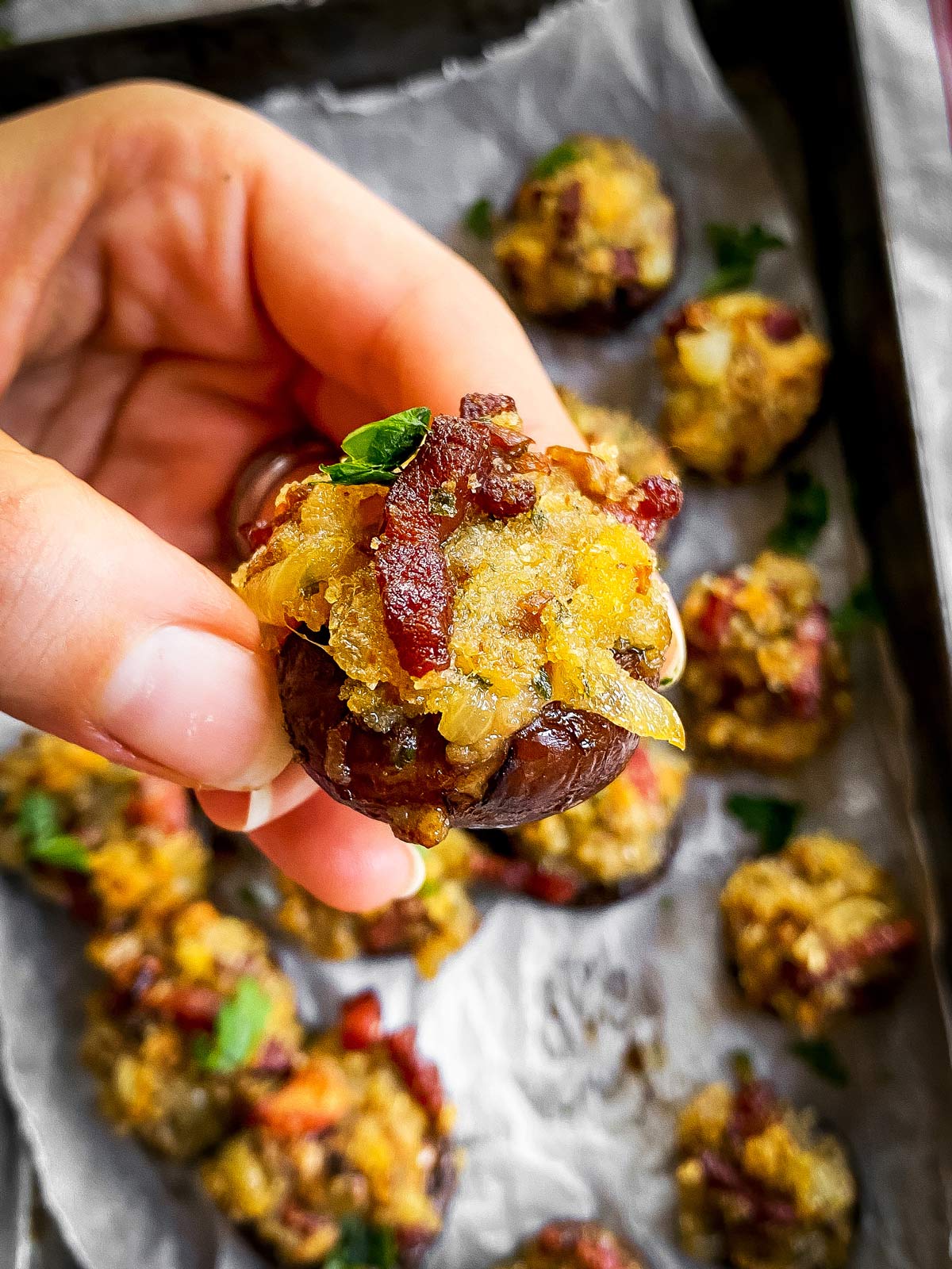 female hand holding a bacon stuffed mushroom