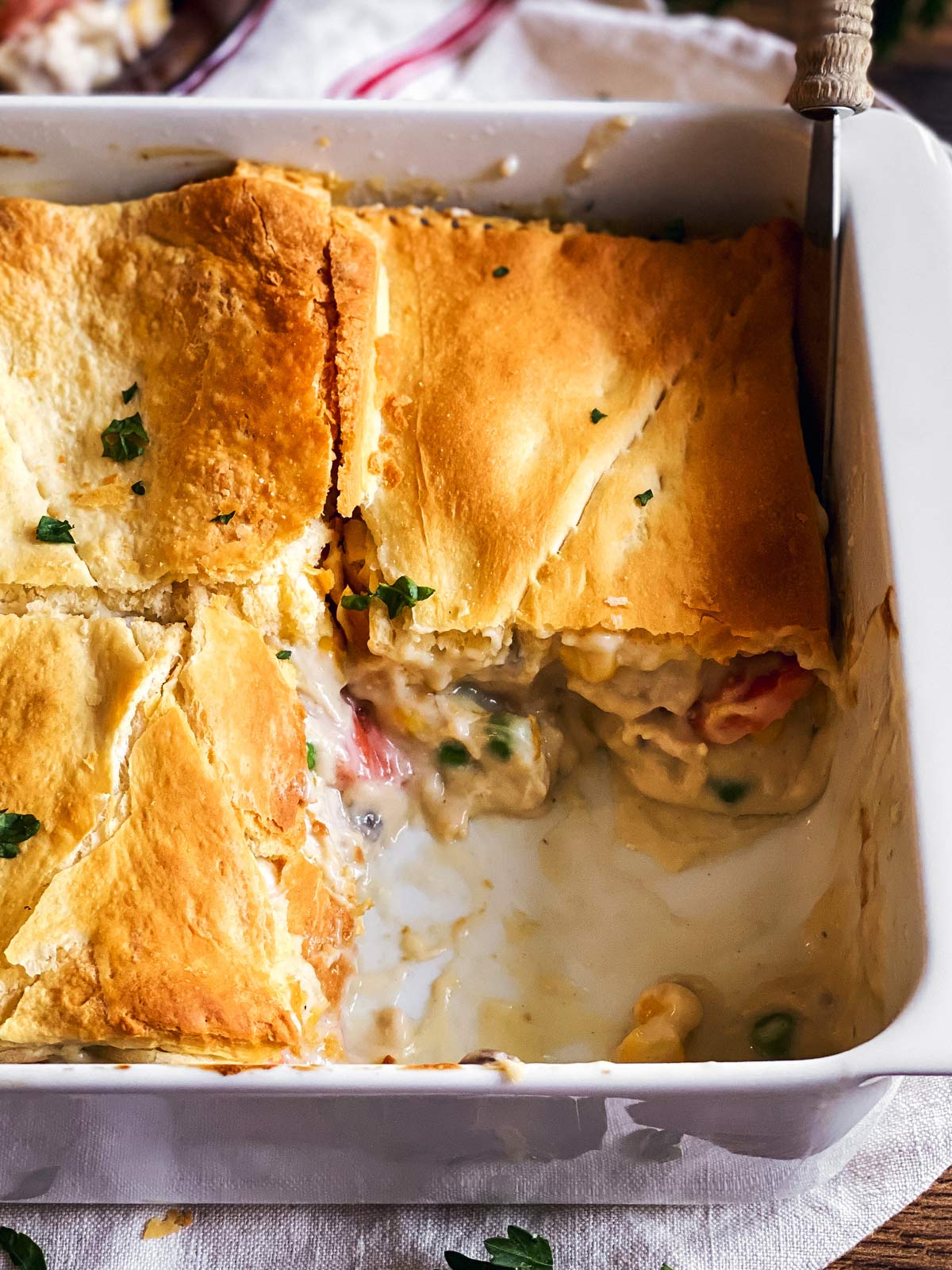 close up photo of turkey pot pie in white casserole dish