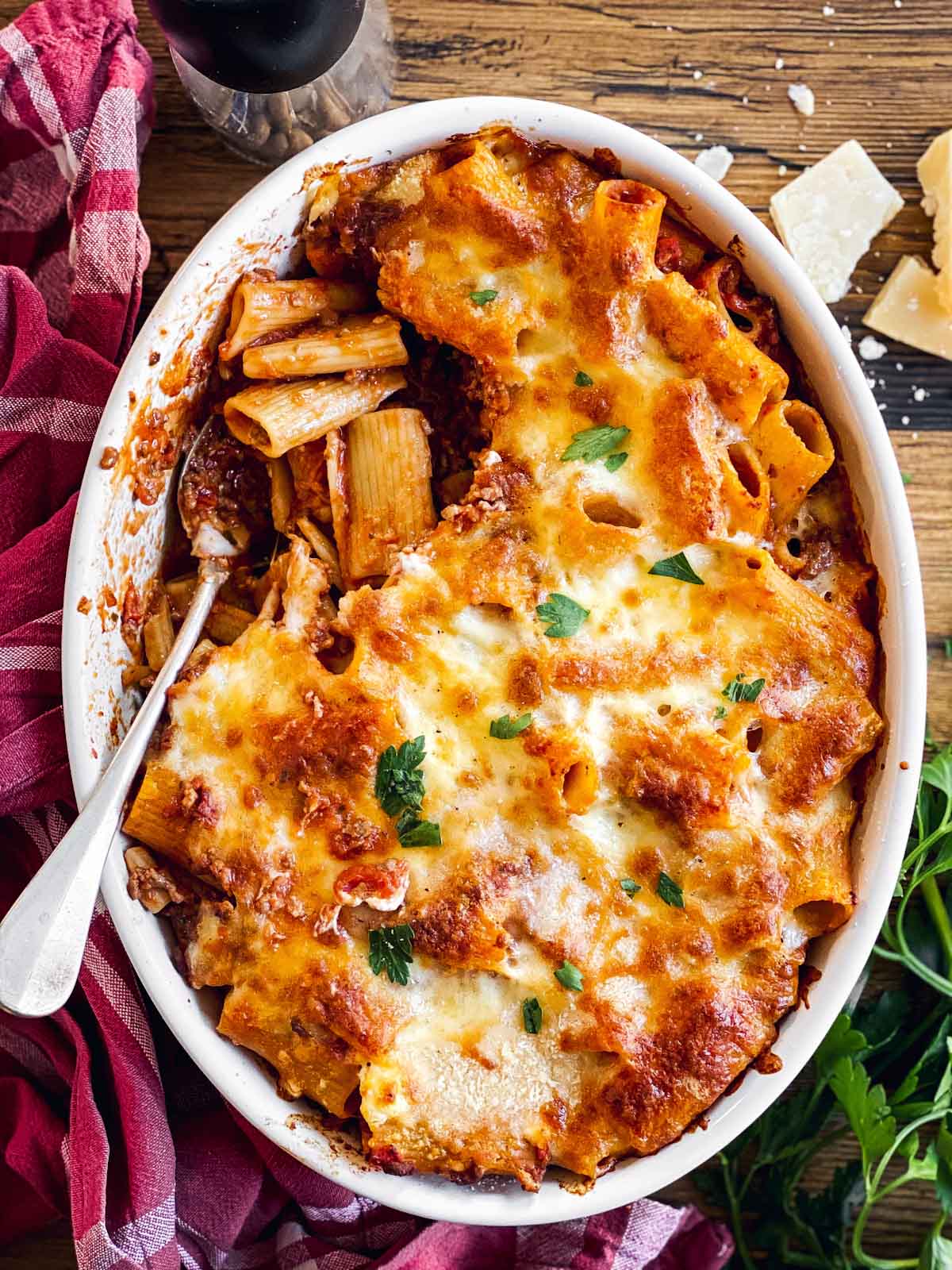 overhead view of baked rigatoni bolognese in white oval casserole dish