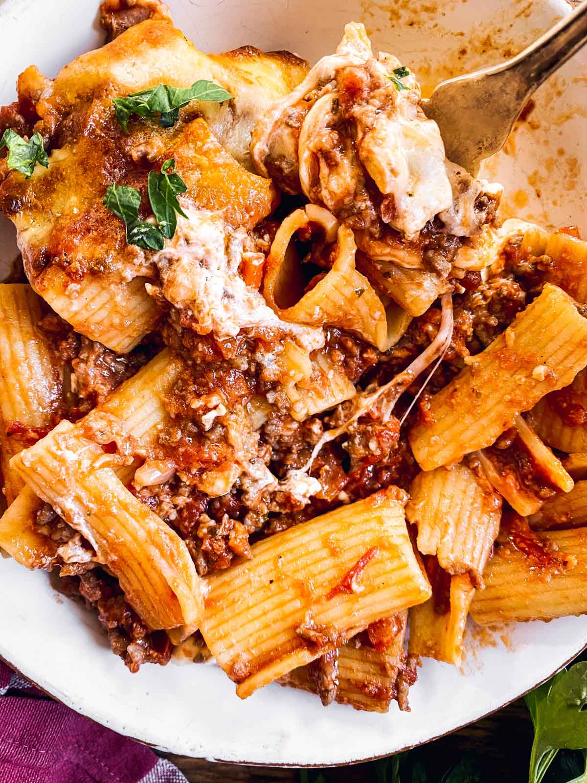 close up photo of baked Rigatoni Bolognese on white plate