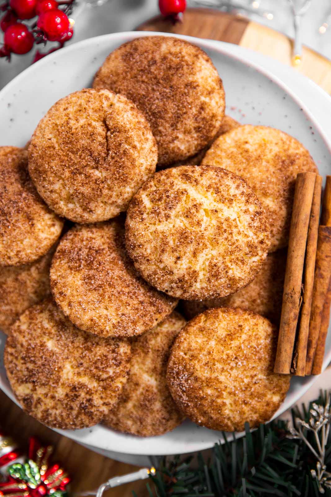 snickerdoodle cookies on white plate with cinnamon sticks and Christmas decorations