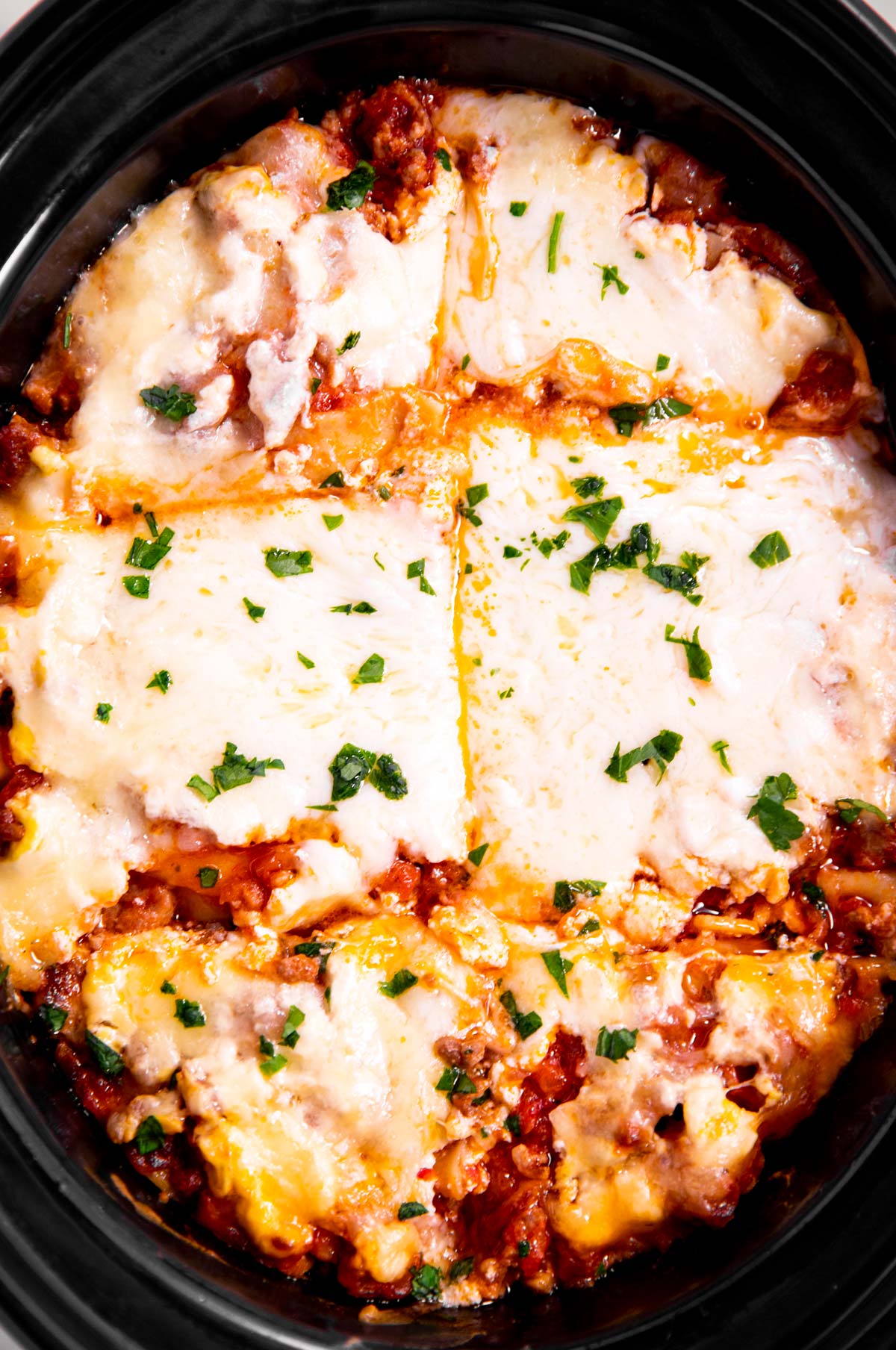 overhead view of lasagna in crockpot cut into six pieces