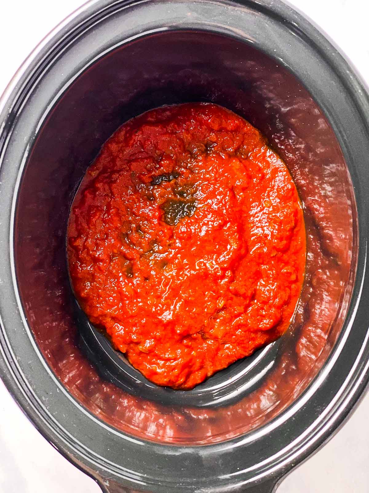 tomato sauce in bottom of black crock