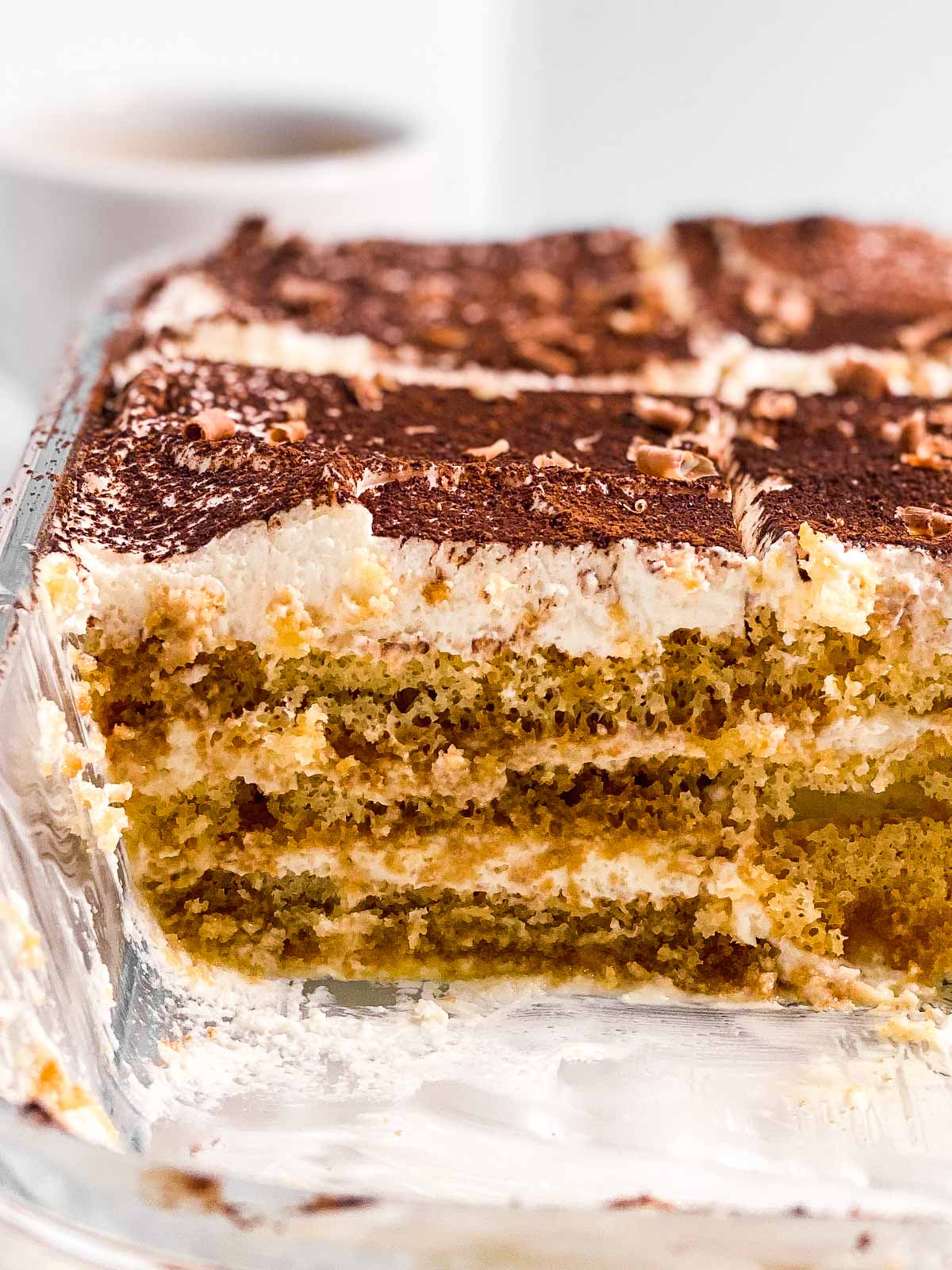 close up photo of sliced tiramisu in glass pan