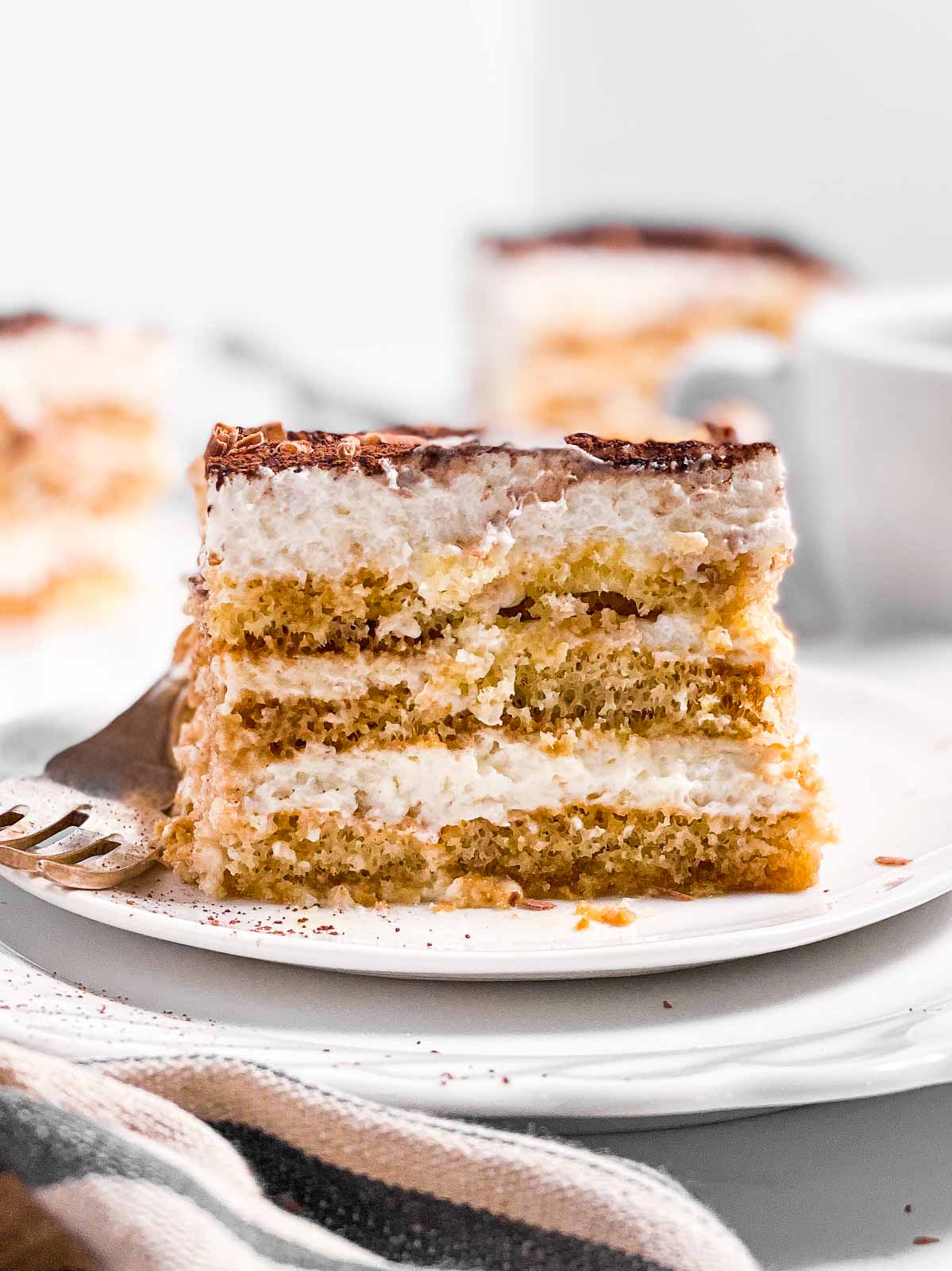 slice of Tiramisu on stack of two white plates