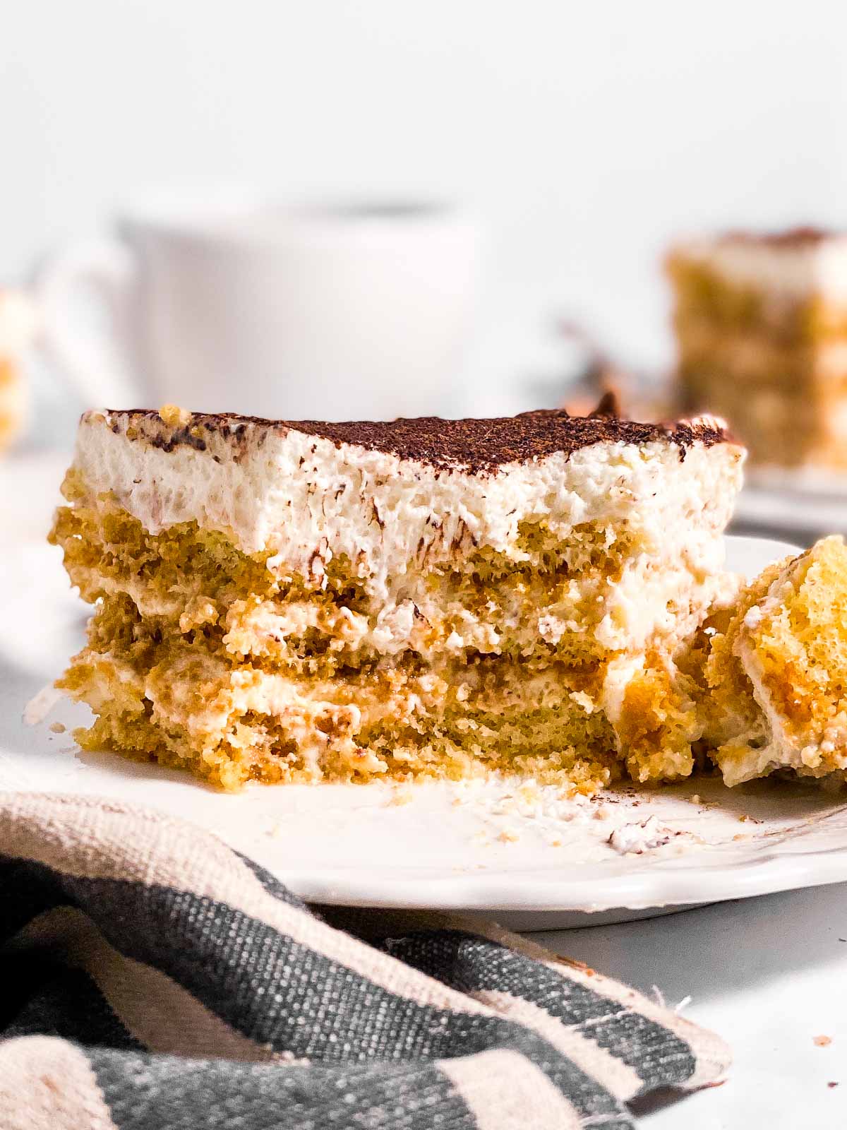 slice of Tiramisu on white plate with bite taken out