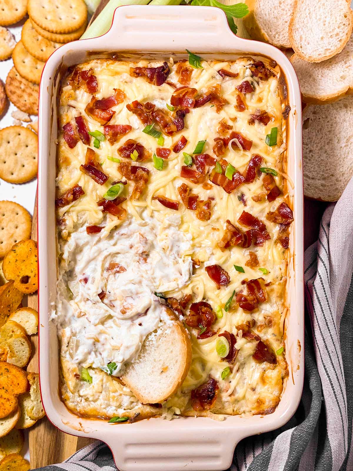 overhead view of hot onion and bacon dip in casserole dish with bread dipped in