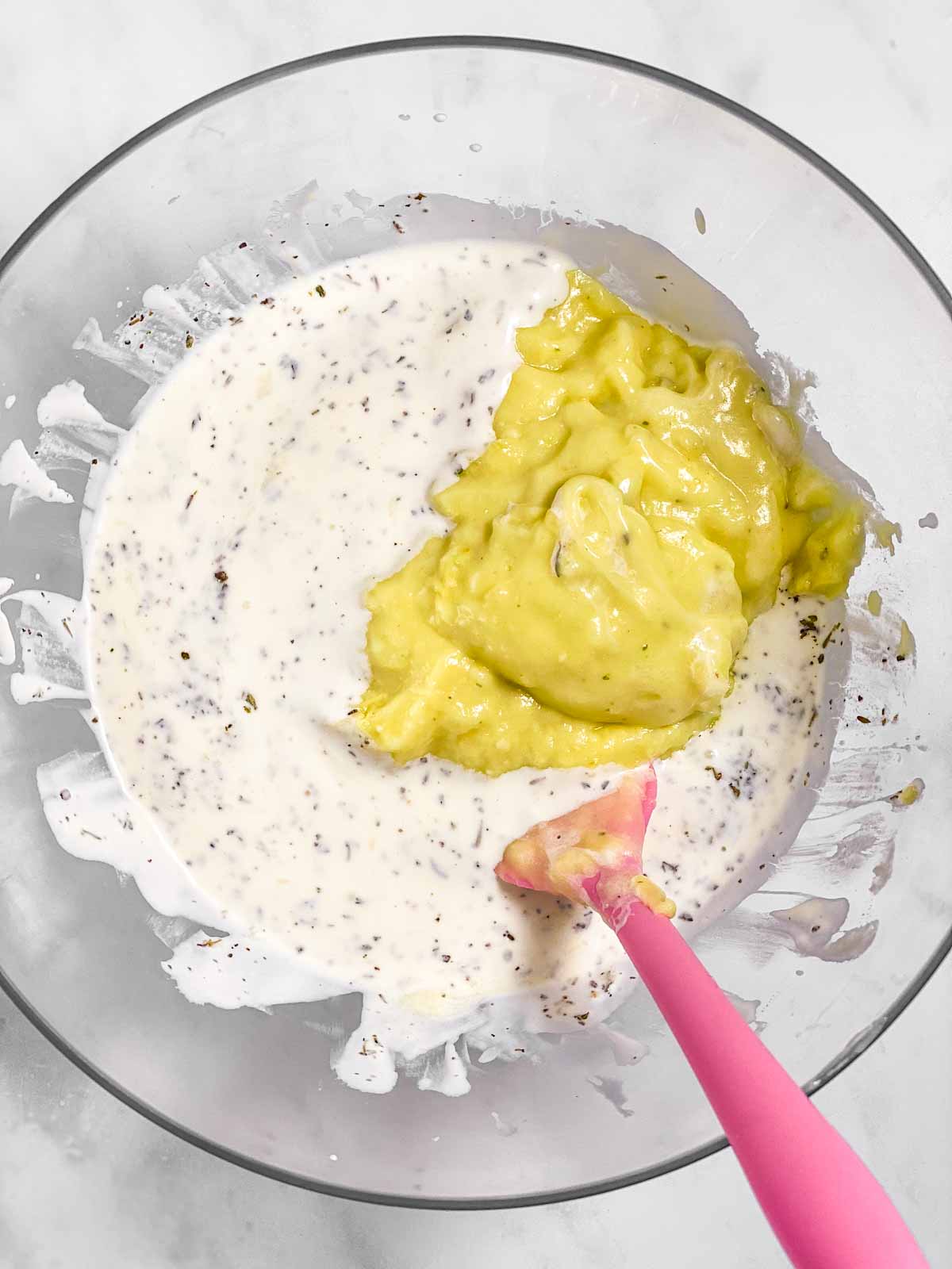 seasoned mayonnaise and cream of chicken soup in glass bowl with pink rubber spatula