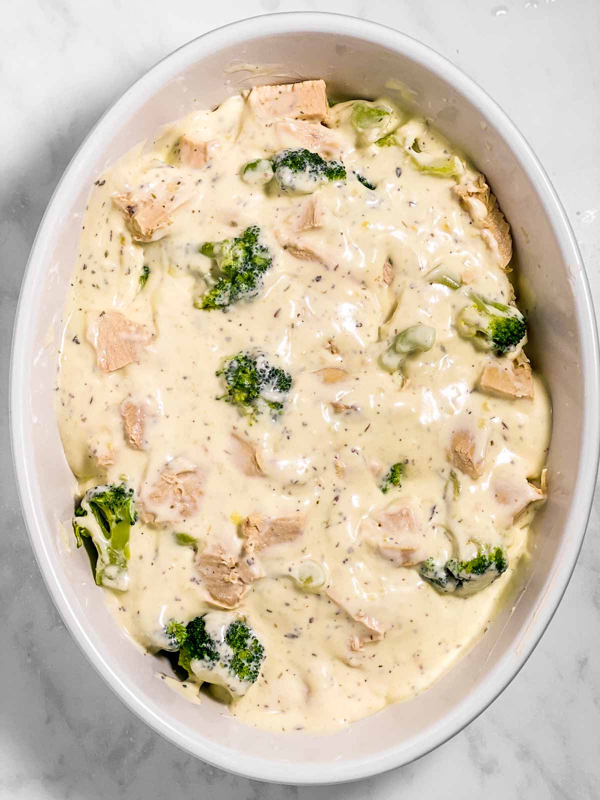 chicken, broccoli and sauce in white oval casserole dish