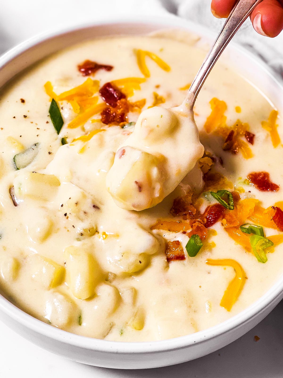 spoon scooping potato soup from bowl