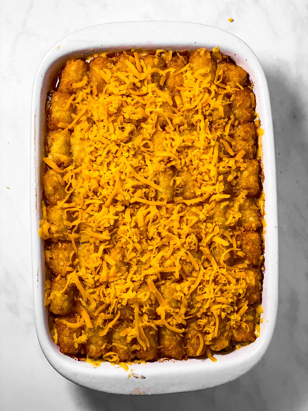 tater tot casserole topped with shredded cheese