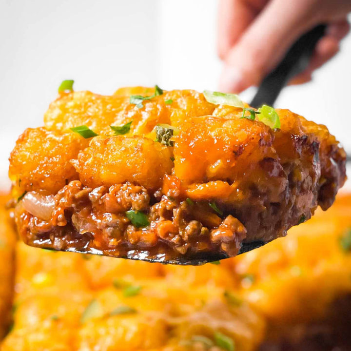 scoop of sloppy joe tater tot casserole on black serving spoon