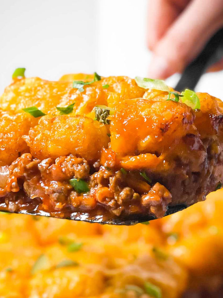 scoop of sloppy joe tater tot casserole on black serving spoon